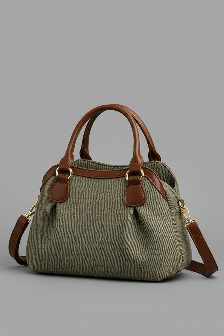 Green handbag with brown handles and strap on a beige background