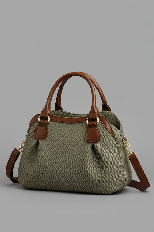 Green handbag with brown handles and strap on a beige background