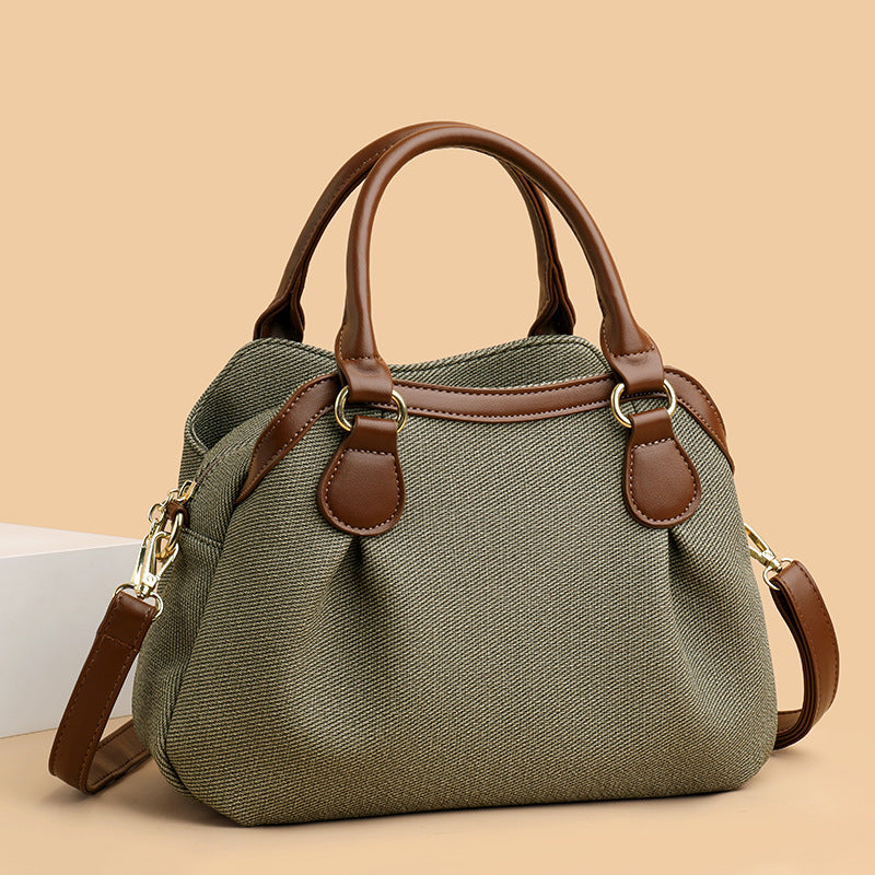 Green handbag with brown leather accents on a beige background