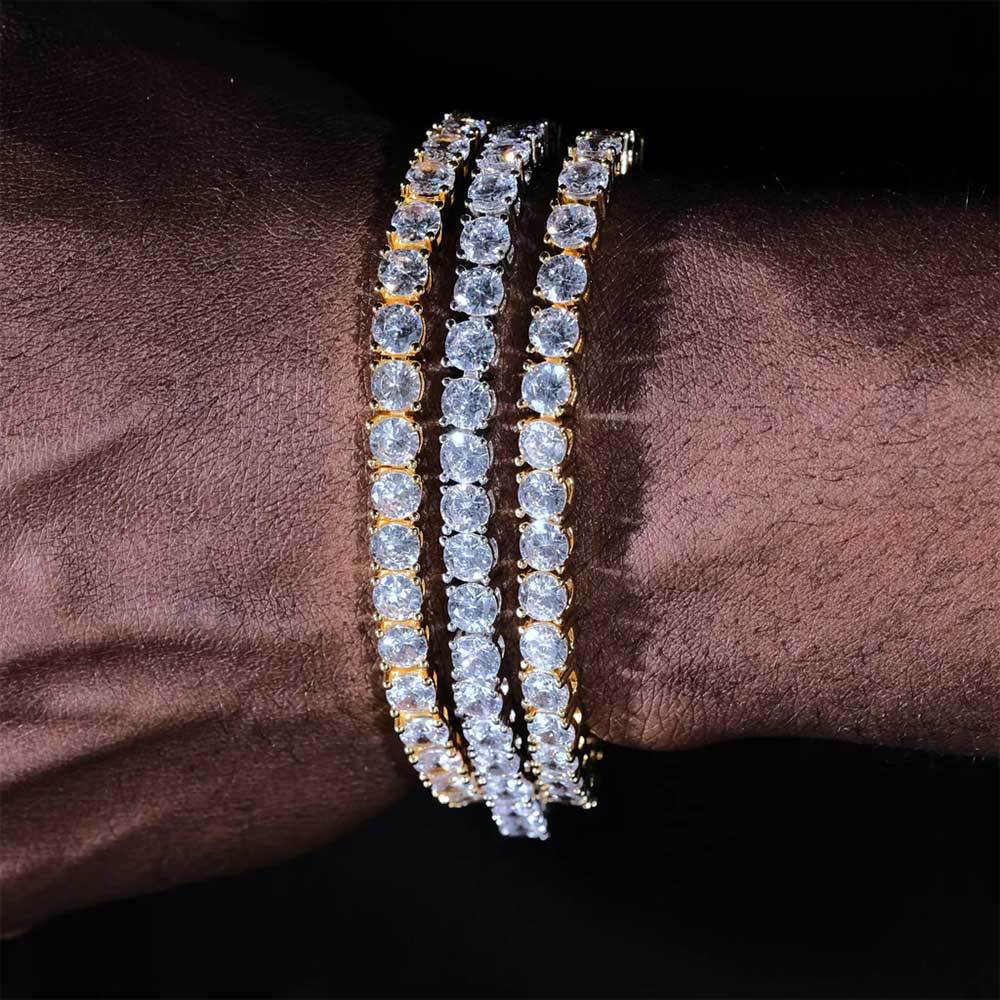 Two diamond bracelets on a wrist against a dark background