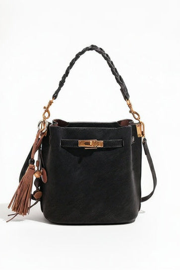 Black handbag with braided handle and tassel on a white background